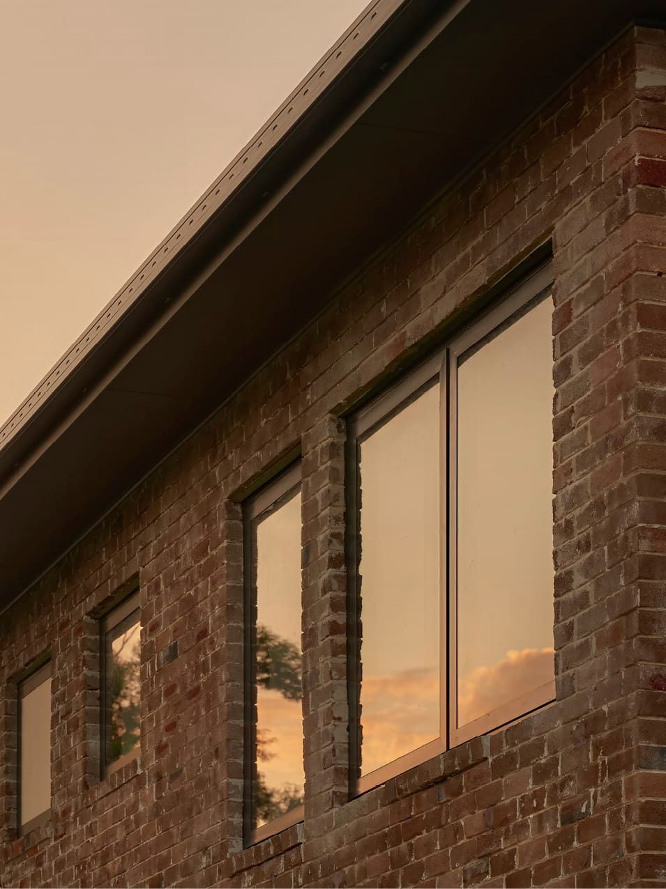 ORIGINAL BRICK BUILDING REVITALISED WITH MODERN WINDOW FRAMES AND ROOF LINES